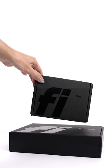 Main déposant une boîte de Fi Mini sur une boîte de Fi Series 3+